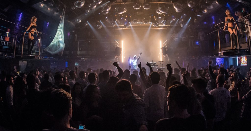 Saxofonista DeeSaxx a DJ na pódiu před zaplněným sálem na velkém eventu