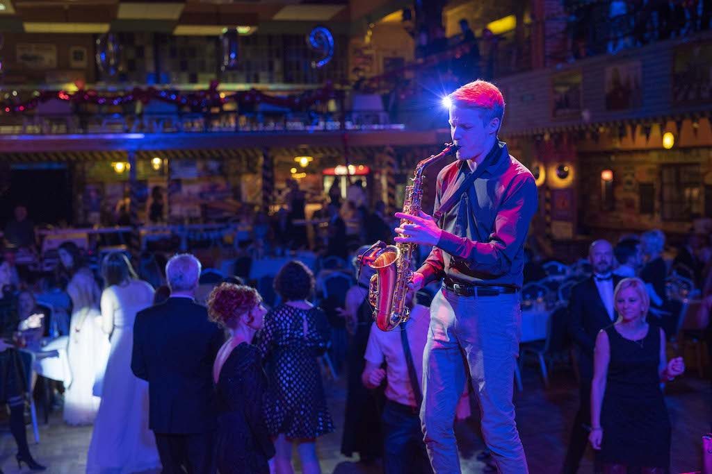 Saxofonista DeeSaxx hraje mezi tančícími hosty na plese v Ostravě